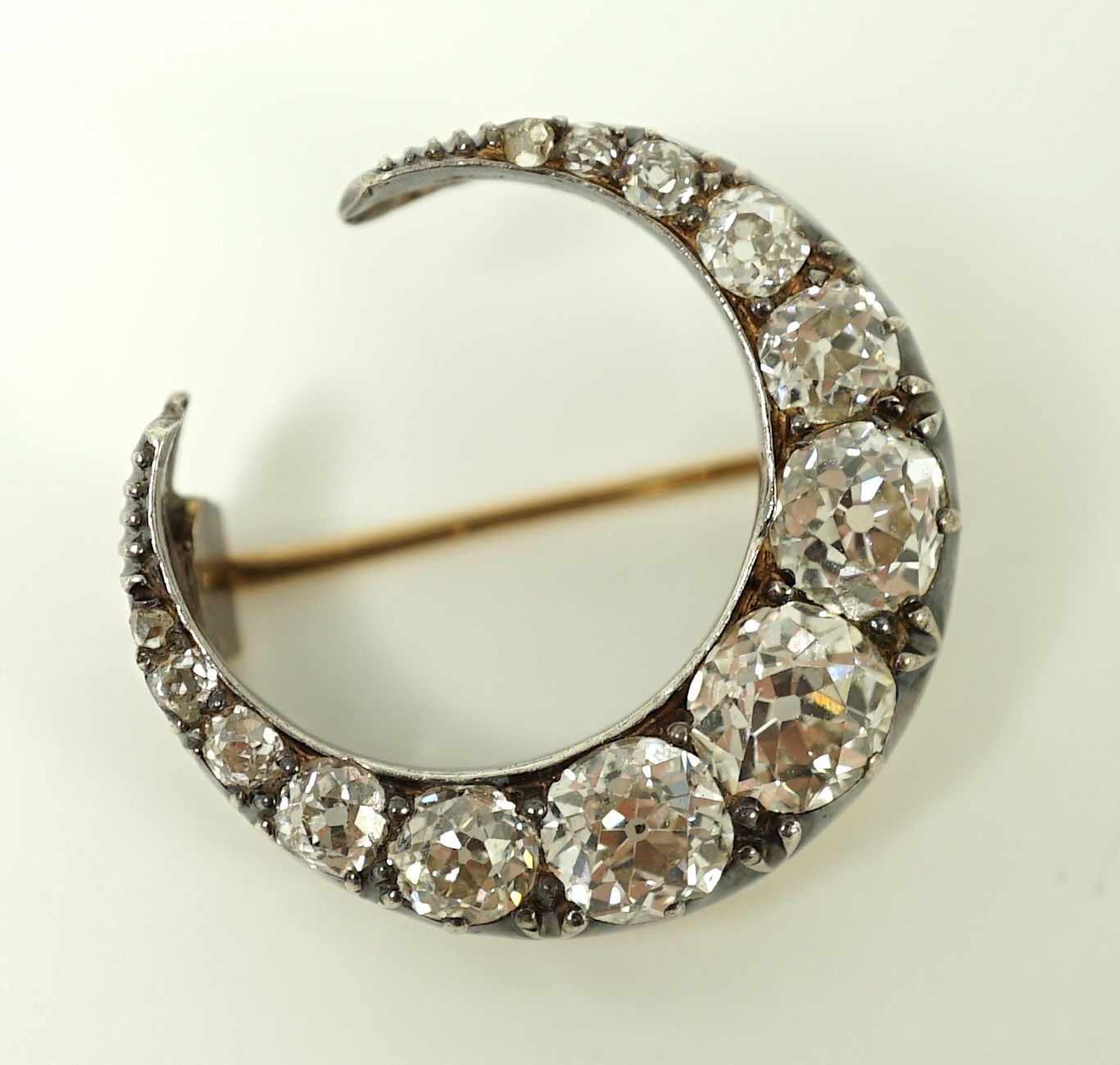 A Victorian gold, silver and graduated thirteen stone diamond set crescent brooch